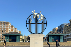 Flight of the Langoustine, by Pierre Diamantopoulo MRSS. It is made of four life-size bronze figures flying through a steel grid. It was inspired by a discarded and mangled lobster pot that the artist had found on Brighton beach. In his imagination, the washed-up object that had seemingly helped the lobsters escape, translated itself into a wider story of human exodus and release – a dash for freedom. Diamantopoulo describes the figures as “at once profound, frivolous and boisterous, occupying the air like a flock of birds and inspired by modern dance choreography”. Bronze casting at Milwyn Foundry and fabrication of the steel grid and assembly by Art Fabrications. The sculpture weighs 2.2 tonnes and measures approximately 3.5 metres high and 3 meters wide. Flight of the Langoustine was inaugurated on the Hove Plinth on 17 September 2023. Flight of the Langoustine, by Pierre Diamantopoulo MRSS. It is made of four life-size bronze figures flying through a steel grid. It was inspired by a discarded and mangled lobster pot that the artist had found on Brighton beach. In his imagination, the washed-up object that had seemingly helped the lobsters escape, translated itself into a wider story of human exodus and release – a dash for freedom. Diamantopoulo describes the figures as “at once profound, frivolous and boisterous, occupying the air like a flock of birds and inspired by modern dance choreography”. Bronze casting at Milwyn Foundry and fabrication of the steel grid and assembly by Art Fabrications. The sculpture weighs 2.2 tonnes and measures approximately 3.5 metres high and 3 meters wide. Flight of the Langoustine was inaugurated on the Hove Plinth on 17 September 2023.